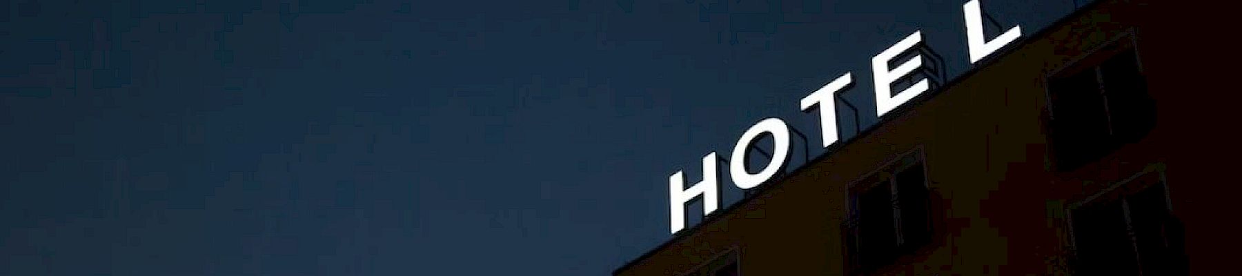 A hotel building sign with the letters "HOTE L," with the "L" slightly separated from the rest, is visible against a dark sky.