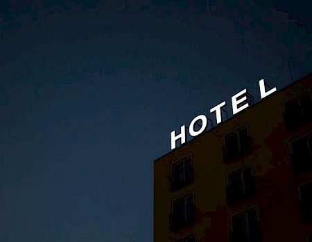 A hotel building sign with the letters "HOTE L," with the "L" slightly separated from the rest, is visible against a dark sky.
